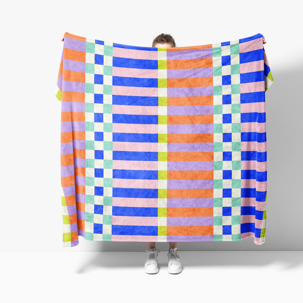 Person holding a colorful checkered blanket against a white background