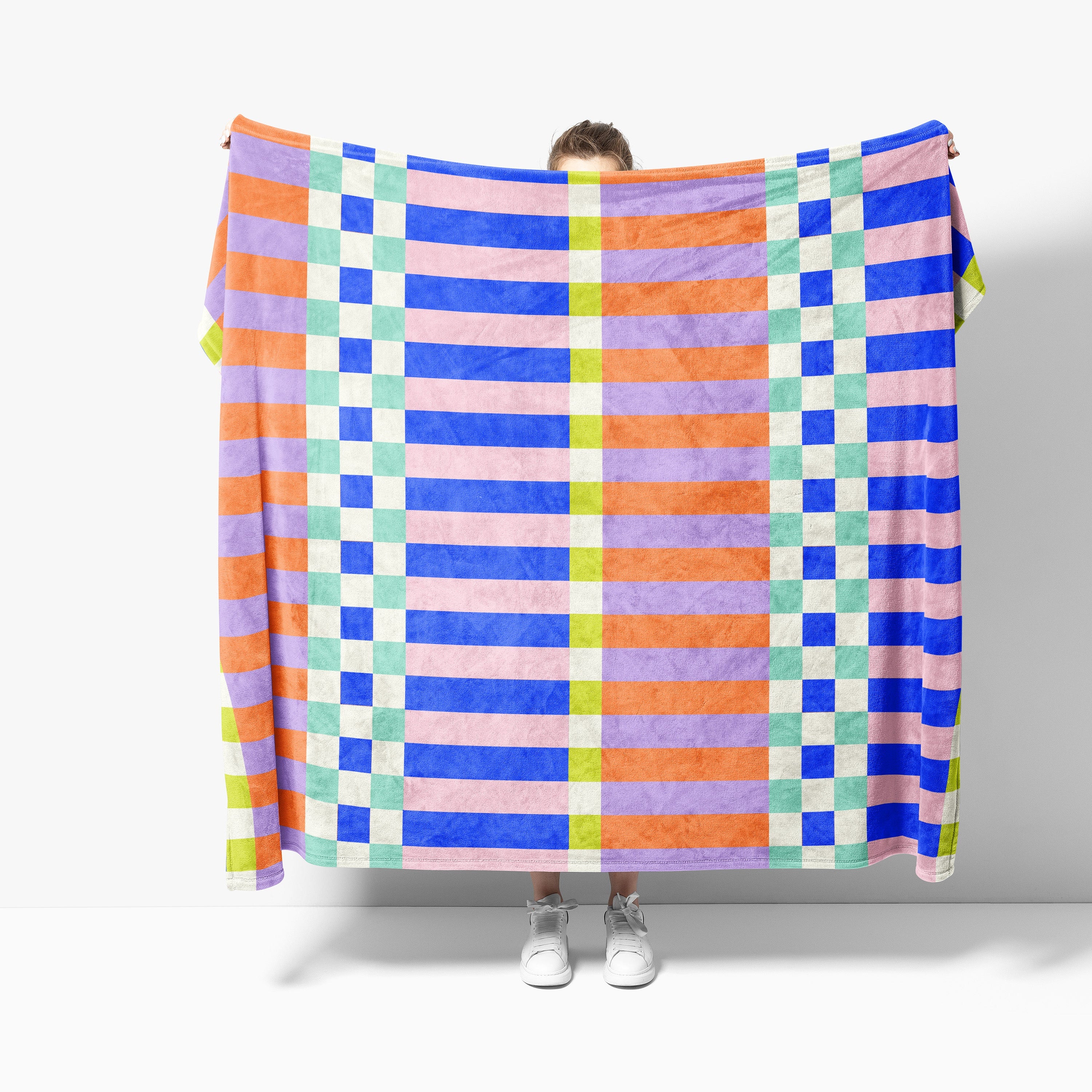 Person holding a colorful checkered blanket against a white background