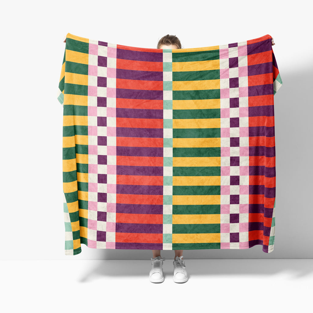 Person holding a colorful checkered blanket against a white background