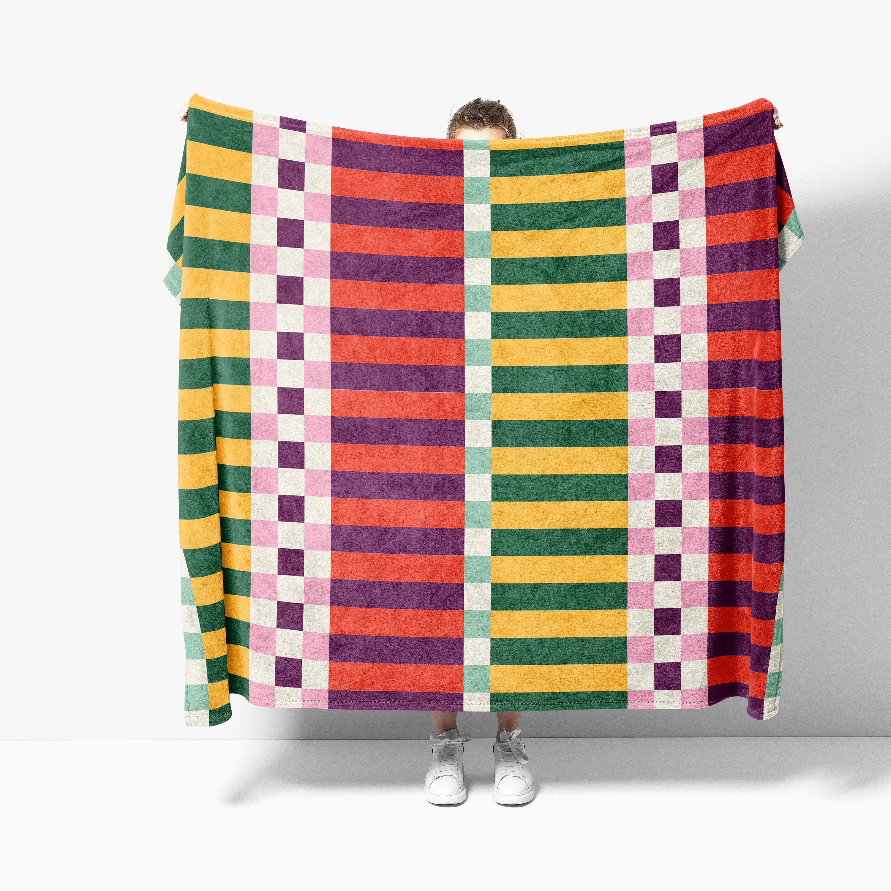 Person holding a colorful checkered blanket against a white background